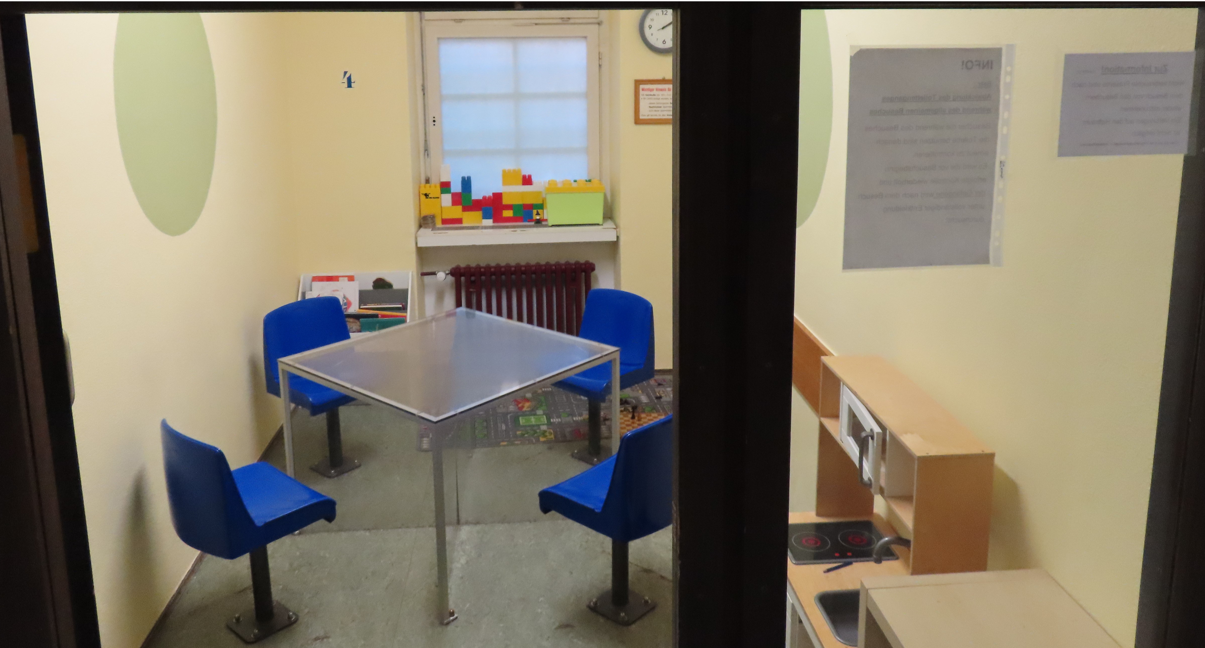 Ein Besucherraum in einer Justizvollzugsanstalt mit Tisch, Stühlen und einer Kinderspielsachenich. 
